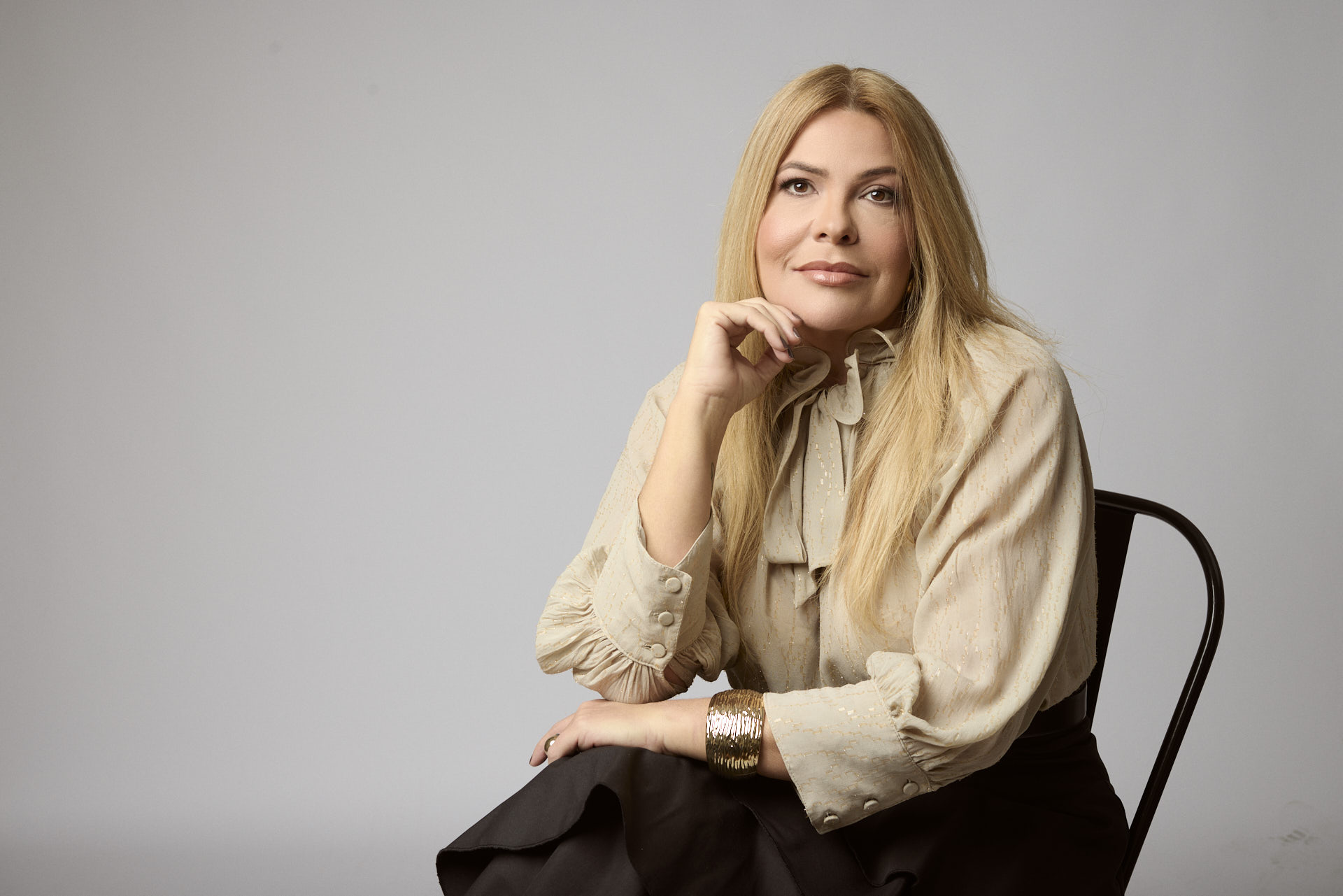 Carla Bittencourt sentada, em estúdio